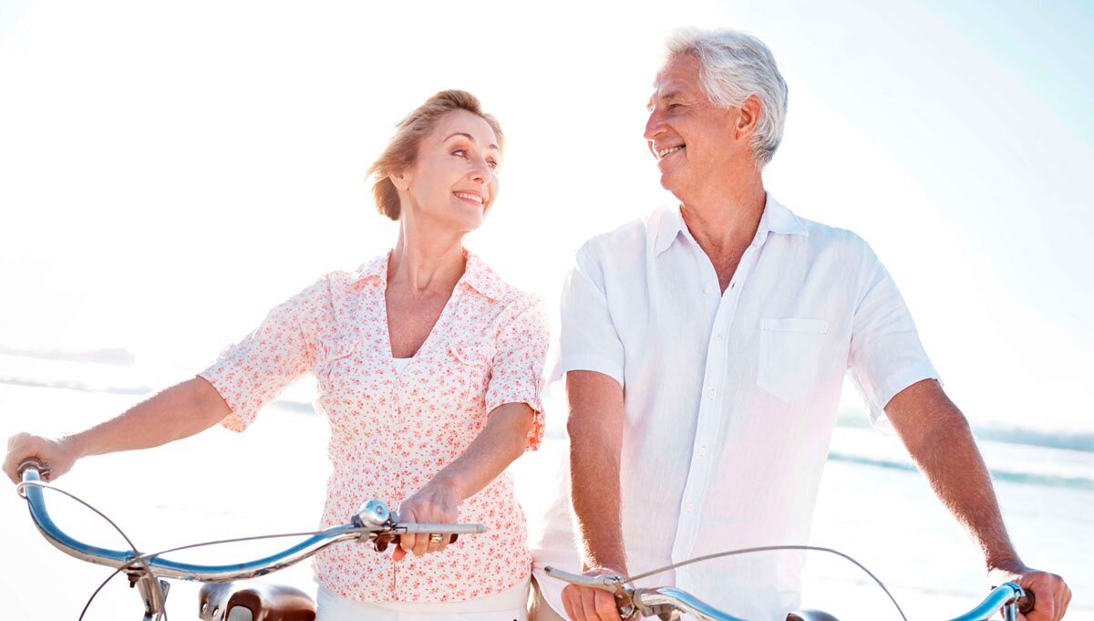 older couple riding bikes on beach