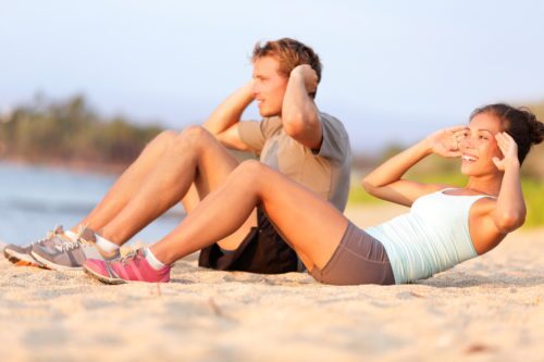 man and woman working out on beach